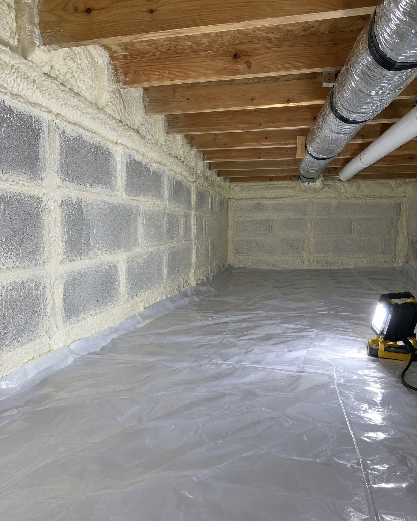 Installer spraying foam insulation in protective gear